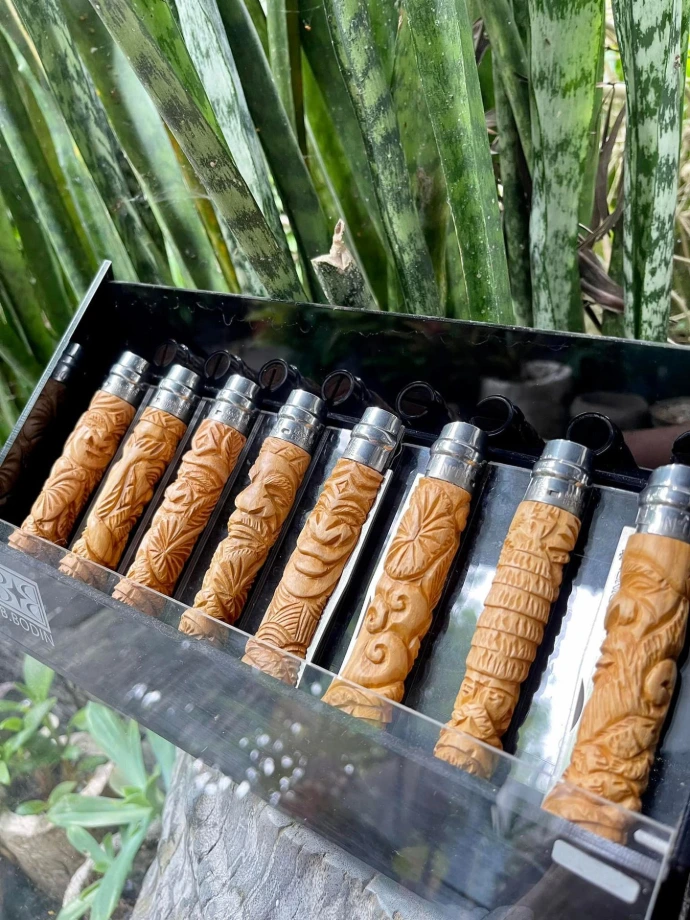 Neuf couteaux Opinel à manche en bois sculpté de motifs variés (visages, feuilles, spirales), signés B. Bodin