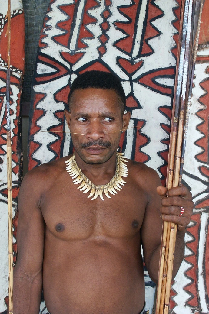 Homme papou portant un collier traditionnel et une lance en Papouasie-Nouvelle-Guinée