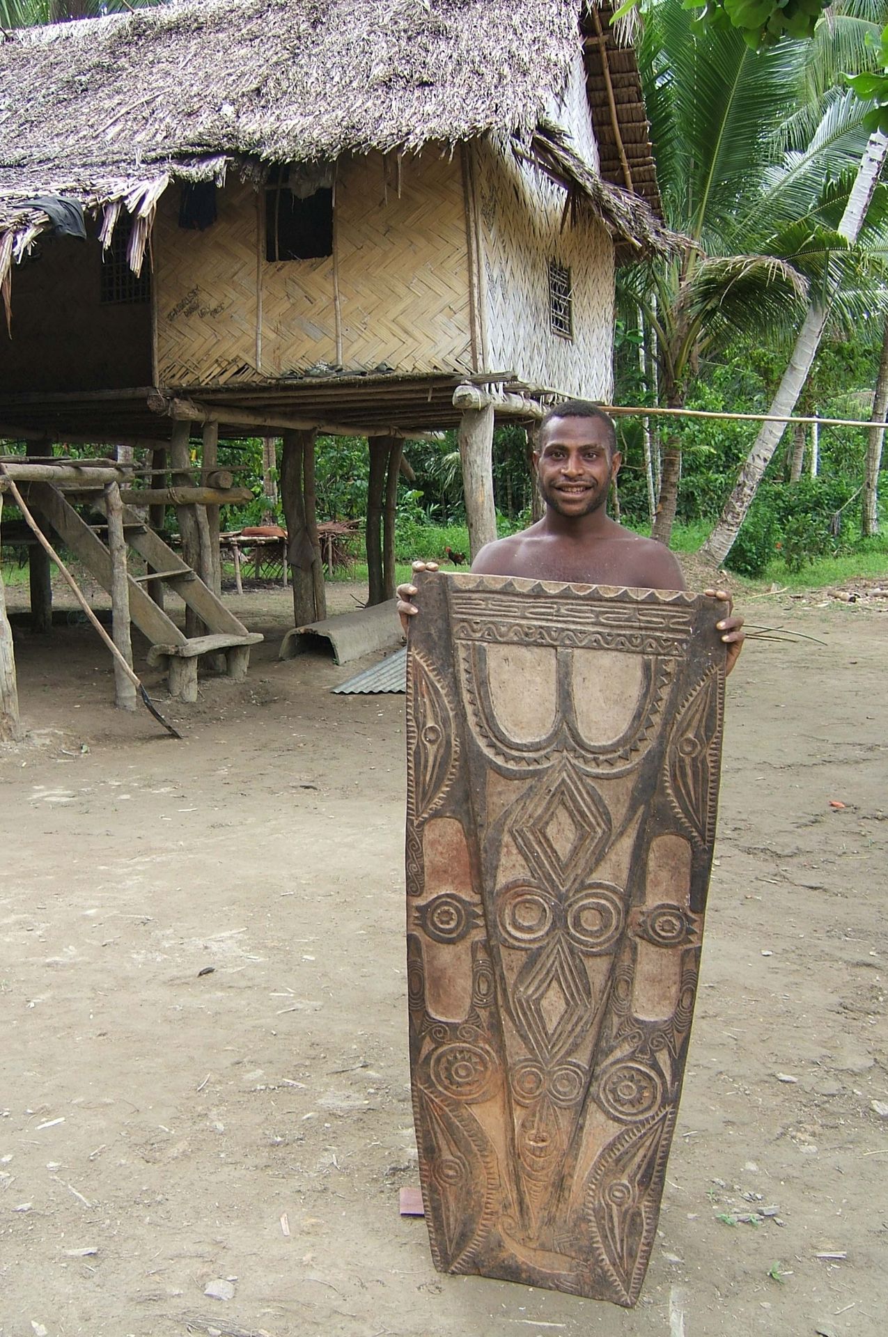 Homme tenant un bouclier sculpté et peint de la région du Keram, Papouasie-Nouvelle-Guinée