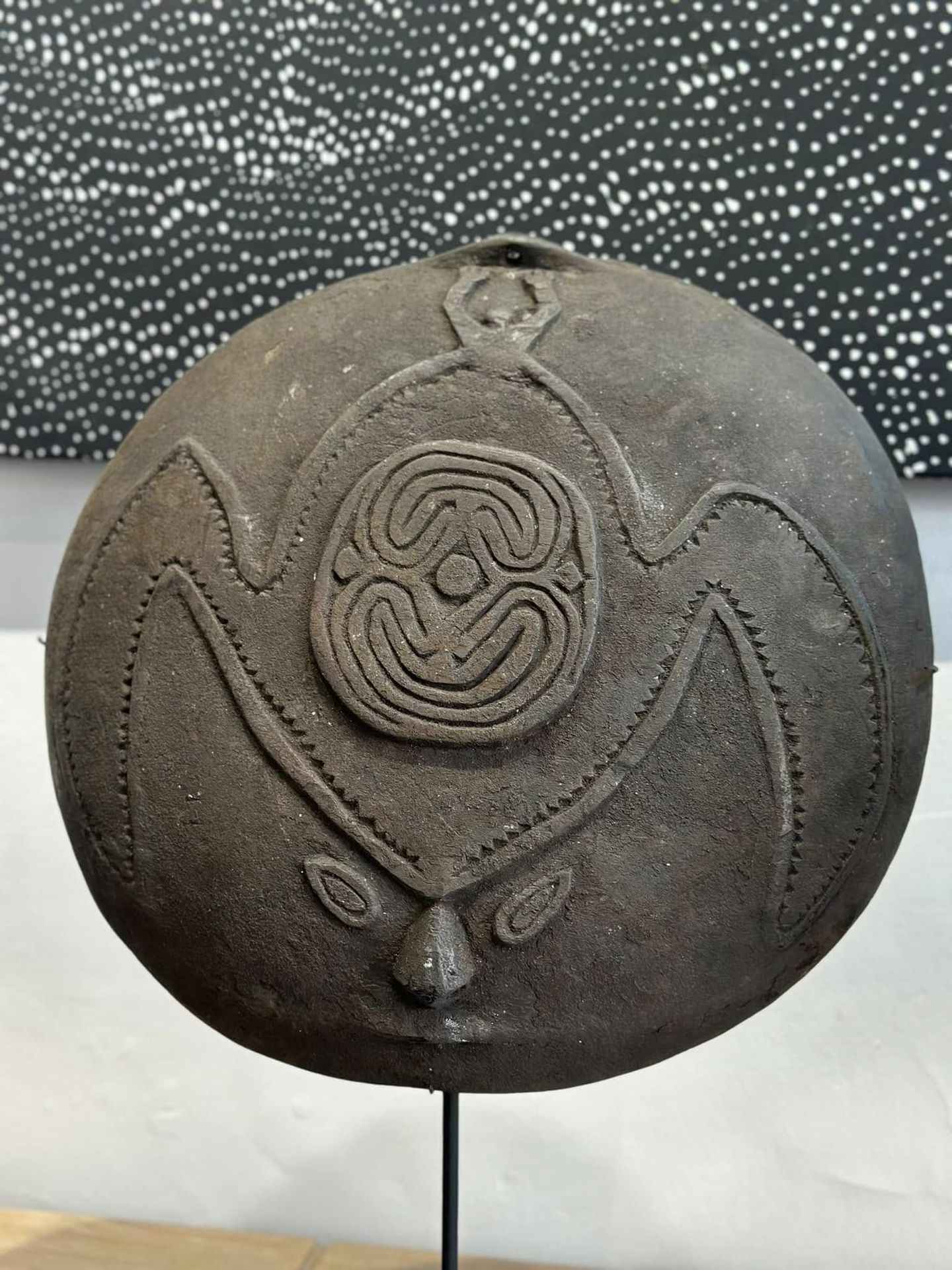 Disque en bois sculpté d'un motif central en spirale entouré de formes ailées dentelées, art papou
